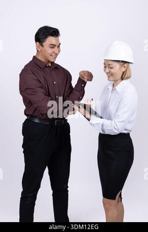 Male and female construction experts looking at clipboard Stock Photo