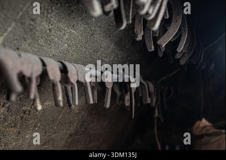 Rusty hand-forged iron hooks and tools stored inside an old blacksmith workshop, showing traditional metalworking craftsmanship and historic industria Stock Photo