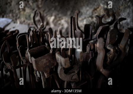 Rusty hand-forged iron hooks and tools stored inside an old blacksmith workshop, showing traditional metalworking craftsmanship and historic industria Stock Photo