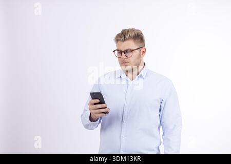Focused young man using smartphone while looking at screen Stock Photo