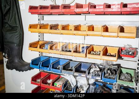 Industrial workshop organization system with labeled plastic storage bins on shelving, holding assorted fasteners and small parts, plus hanging rubber Stock Photo