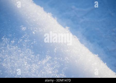 Detailed snow surface texture with glittering ice crystals and smooth drift ridge, minimal winter background in cool blue tones, natural frozen patter Stock Photo