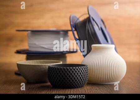 Plastic filament for 3D printer and printed products on a wooden table. Stock Photo