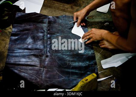 Shoemakers working by hand in a small workshop in Hoi An, Vietnam, crafting and repairing footwear using traditional manual techniques Stock Photo