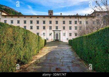 REGGELLO, TUSCANY - ITALY - DECEMBER 7, 2025 Front view of the Vallombrosa Abbey. A stone path through green hedges leads to the monastery entrance Stock Photo