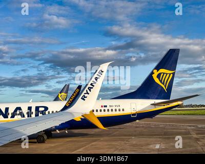 Tails of Ryanair aircraft parked on airport apron near runway under cloudy sky Stock Photo