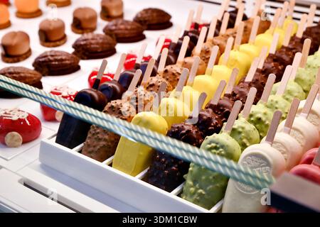 A display case with artisanal ice cream popsicles on sticks and small pastries in a bakery in Paris - France Stock Photo