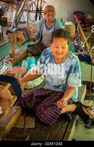 Thailand, Isaan, Sakon Nakhon, Donkoi Sustainable Village project, woman winding dyed cotton thread on large wooden bobbin, ready to be hand woven Stock Photo