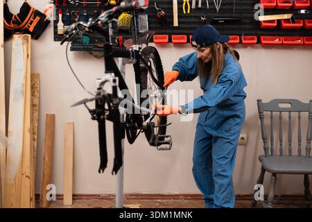 modern bicycle hanging on a professional repair stand in a cycle workshop, featuring tools, equipment. concept of professional bike service. Stock Photo