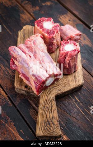 Butcher style raw Lamb oxtail segments with kitchen fork on rustic wooden table, traditional meat for stock and slow cooking. Stock Photo
