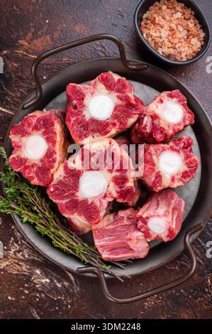 Raw Oxtail pieces in pan with fresh thyme, top view rustic food scene showing collagen rich beef for stock. Stock Photo