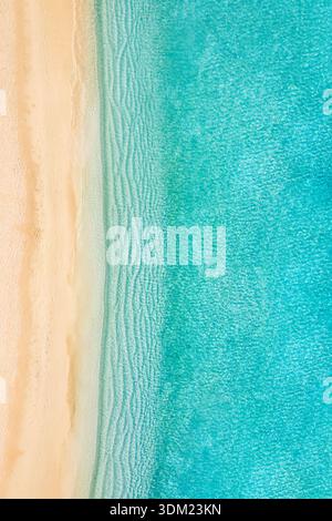 Dreamy beach vertical aerial turquoise water sand abstract top view stunning paradise coastal destination texture pattern background. Ocean waves Stock Photo