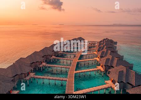 Amazing Aerial Maldives luxury overwater resort dramatic sunset sky stunning breathtaking paradise calm ocean water exotic coastal travel wall art Stock Photo