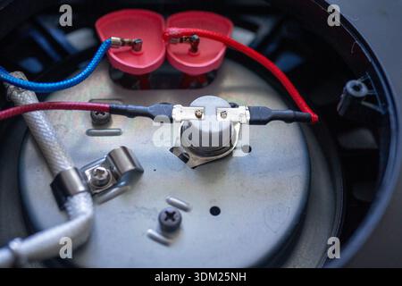 Macro view thermostat and wiring, metal contact and white insulated lead, adjustment screw and mounting Stock Photo