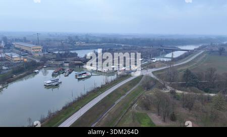 Aerial view of the Isola Serafini dam complex on the Po River, featuring navigation locks, boats, and associated energy infrastructure Stock Photo