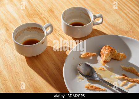 Empty espresso cups and croissant crumbs on white plate Stock Photo