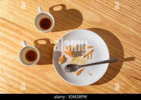 Empty espresso cups and croissant crumbs on white plate Stock Photo