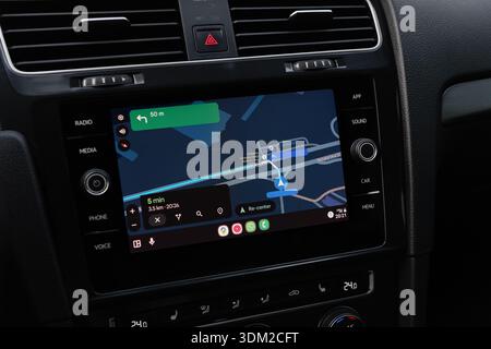 Google maps navigation on screen in modern car. Volkswagen car interior - close-up shot of infotainment system with Android auto screencast. Stock Photo