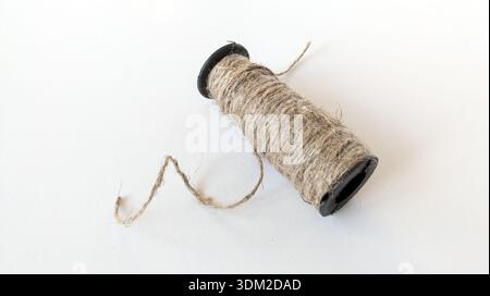 Spool of coarse jute rope wound on a black base. Stylish eco-material. Isolated on white background. Stock Photo