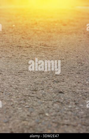 Close-up of Asphalt Road Surface with Golden Sunlight Flare. Asphalt texture. transportation infrastructure. High quality photo Stock Photo