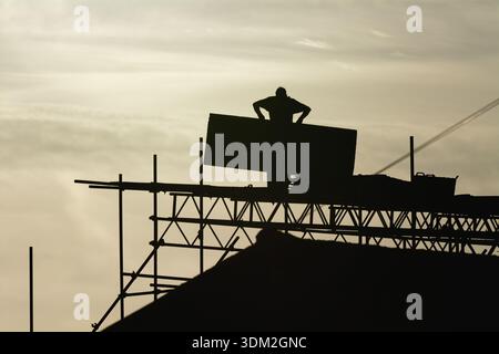 A builder working on scaffolding on a private house about to undergo renovation to a extension to the property Stock Photo