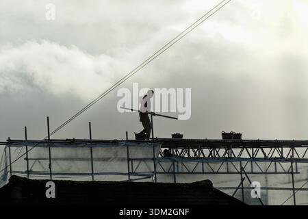 A builder working on scaffolding on a private house about to undergo renovation to a extension to the property Stock Photo