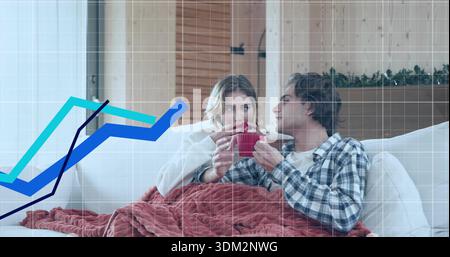 Sipping couple in flannel sitting on home sofa under rust blanket, holding red mugs with charts Stock Photo