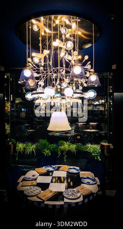 Dining area in Andaz Amsterdam Prinsengracht hotel’s glass-enclosed restaurant, featuring a dramatic gold chandelier with glass shades over a checkere Stock Photo