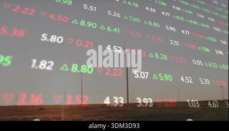 Displaying translucent market-data overlay covering wind farm at dusk, showing turbines and tickers Stock Photo