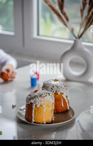 Side view of two traditional Easter kulich placed on a table. Holiday preparation and festive pastry visible. Stock Photo