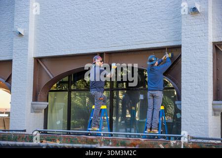 Savannah, Georgia, USA - October 22, 2025: Two men on step ladders work on a restoration project in historical district. Stock Photo