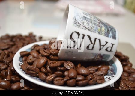 Coffee beans spilling from Paris souvenir cup Stock Photo