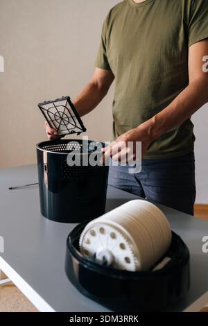 Vertical cropped shot of unrecognizable man holding air humidifier filter, cleaning and maintaining optimal humidity levels in home, promoting clean Stock Photo