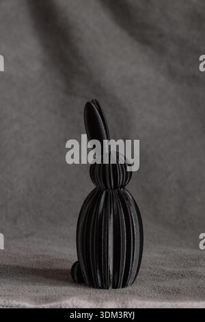 Black plastic rabbit figurine, 3D printed on grey fabric, made in Easter theme and as a souvenir Stock Photo