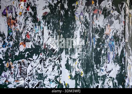 A weathered urban wall in New York City covered in layers of shredded and torn paper poster fragments, creating an accidental abstract collage. Stock Photo