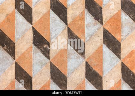 Bold chevron tile pattern in warm earth tones creates a dramatic, classic backdrop. Muted oranges, browns, and beige convey vintage warmth ideal for w Stock Photo