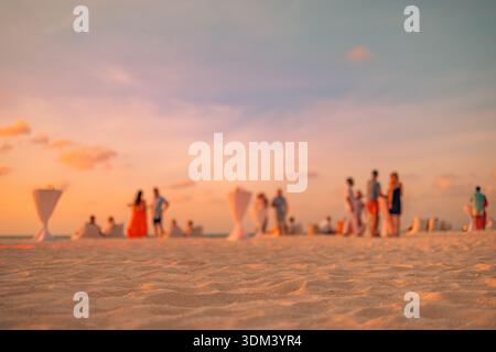Blurred sunset beach party people background. Defocused beachfront holiday relax tropical ocean summer social scene copy space Stock Photo