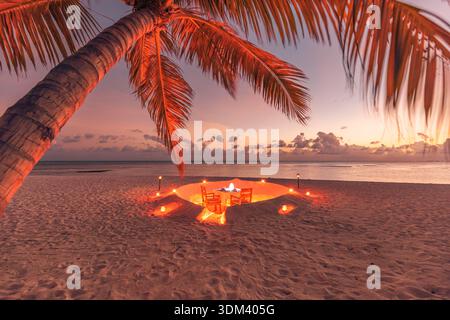 Romantic dinner setting on tropical beach destination dining with ocean view sunset atmosphere. Love couple vacation tourism Stock Photo