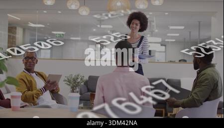 Presenting woman in striped top and overalls speaking in modern office lounge, with tablet overlays Stock Photo