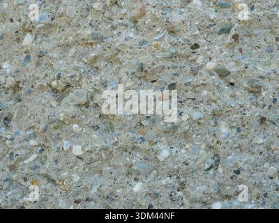 Uneven concrete wall with embedded pebbles. Close-up. Suitable for background and text areas. Copyspace. Stock Photo