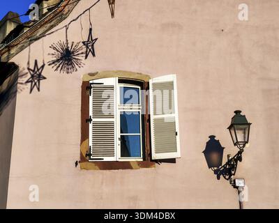 Pink facade with white window and antique street lamp whose shadow falls on the wall, Old Town, Strasbourg, Bas-Rhin, Alsace, France Stock Photo