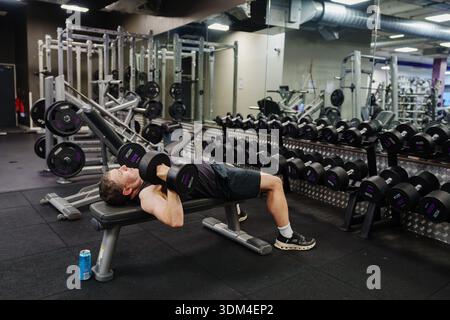 Man doing dumbbell press on bench at commercial gym Stock Photo