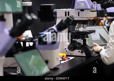 Modern laboratory with professional microscopes. Female scientist is researching samples on a computer. Selective focus. Stock Photo
