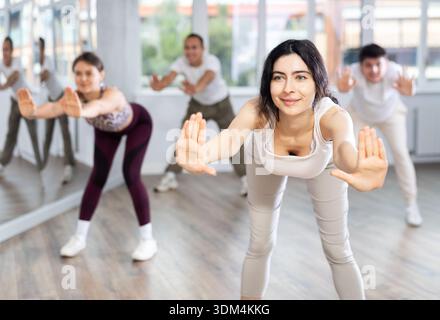 Young brunette warming up with group in dance class Stock Photo