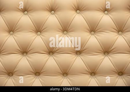 Beige leather upholstery with tufting pattern and decorative buttons background Stock Photo