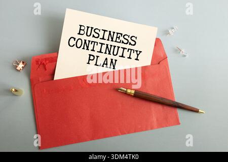 A green spiral notebook with a stack of money in the pocket and the words Business Continuity Plan written on it Stock Photo