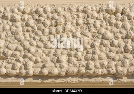 Textured cream stucco wall with an uneven decorative bumpy relief surface detail Stock Photo
