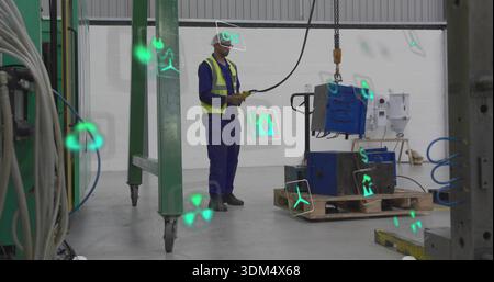 Operating worker in hard hat in shop, controlling hoist with remote lifting blue machine on pallet Stock Photo