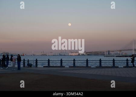 Full Moon Rising Over the Port of Yokohama and Bay Bridge at Twilight from Yamashita Park Stock Photo