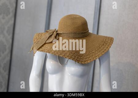 Elegant brown wide brim straw hat, stylish summer fashion accessory for sun protection. This classic headwear for women on mannequin represents vacati Stock Photo
